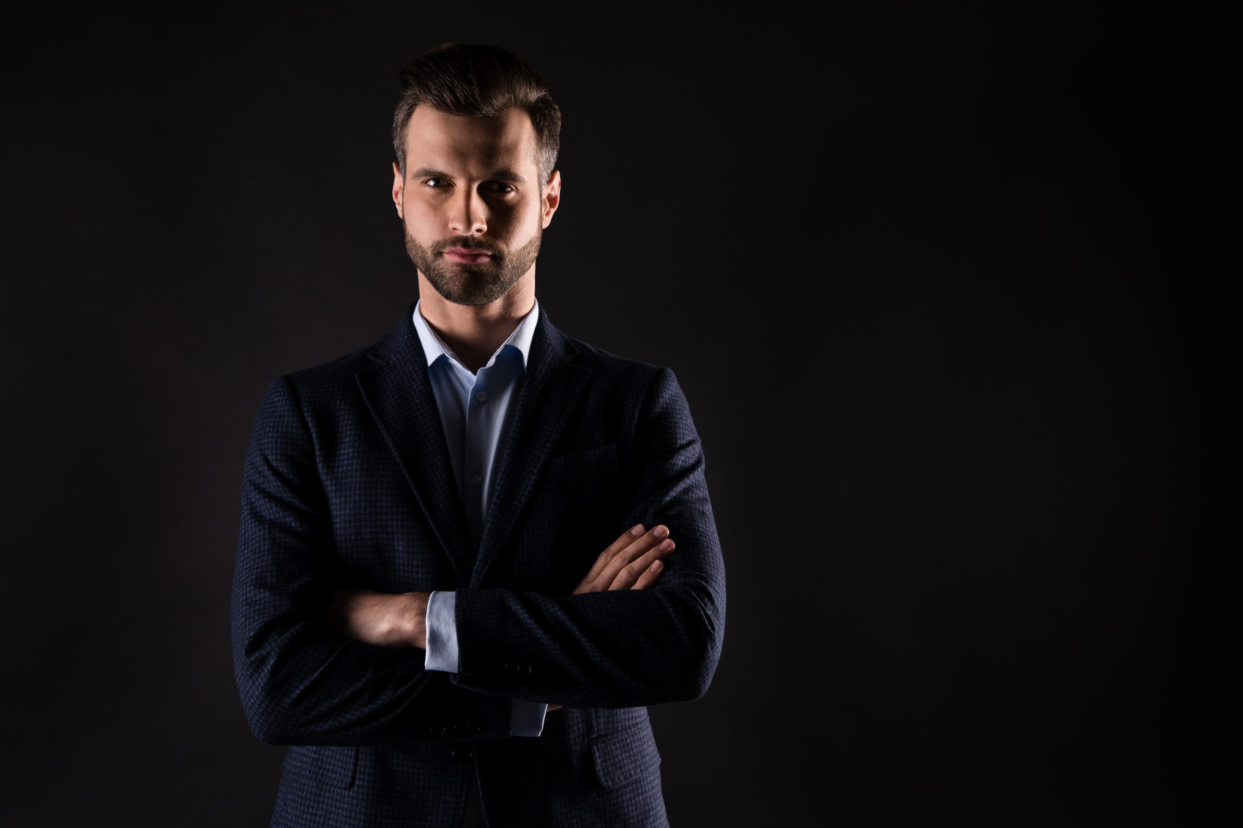 Professionnel du droit en costume sombre, bras croisés, incarnant la rigueur et la confiance. L'excellence juridique, à votre portée, illustrée par une posture déterminée sur fond sombre.