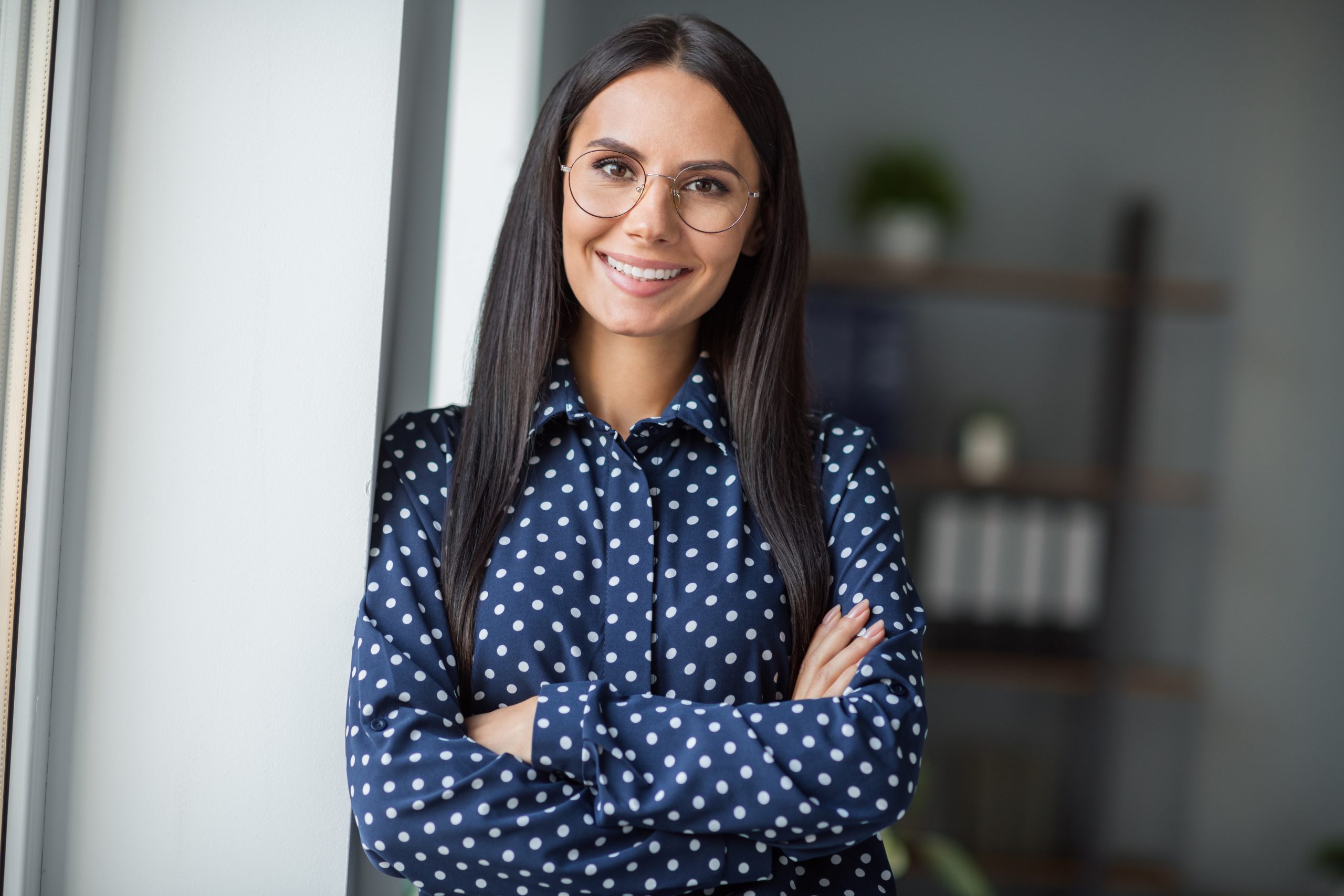 Jeune femme souriante en tenue de personnel médical, assise sur un bureau, symbolisant le professionnalisme et le bien-être dans le secteur de la santé, présenté sur madagasy.com.