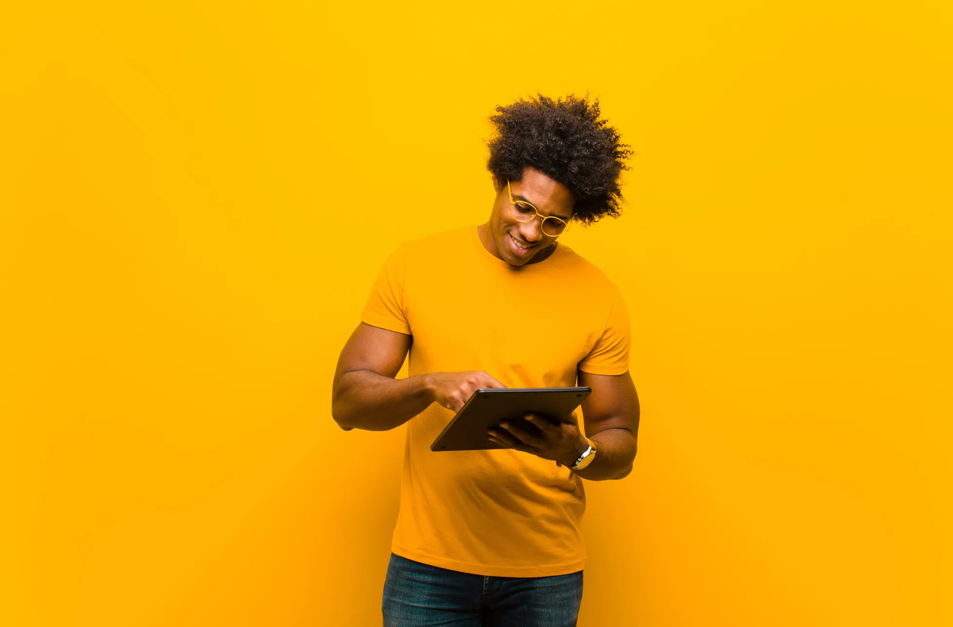 Personne portant un t-shirt jaune, tenant et interagissant avec une tablette numérique, devant un fond jaune lumineux, illustrant la technologie et la simplicité d'utilisation, promues par Madagasy.com à Madagascar, avec un accompagnement en innovation.