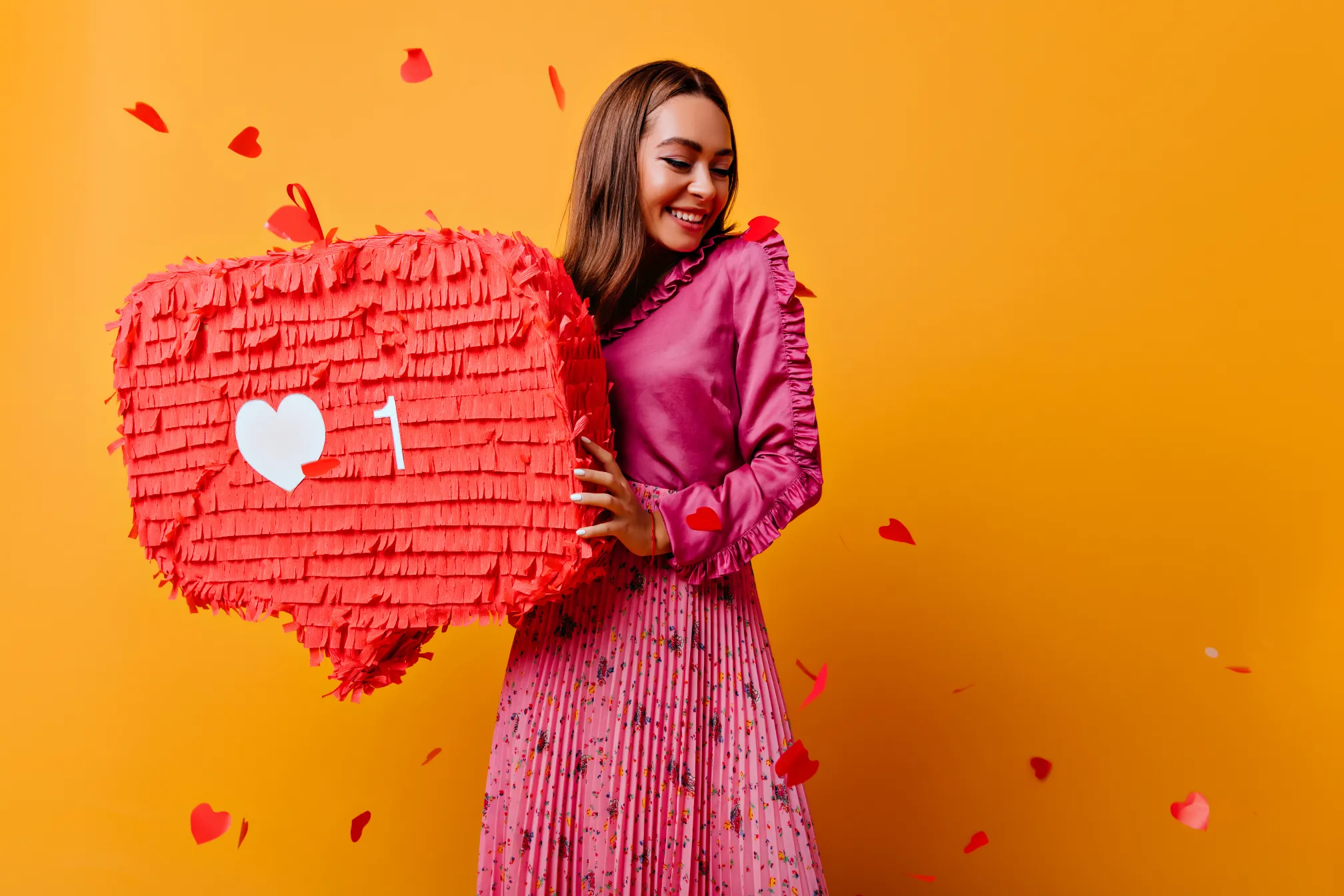 Personne tenant une piñata rouge en forme d'icône de notification avec un cœur et le chiffre 1, représentant l'engagement sur les réseaux sociaux et le Marketing digital promu par Madagasy.com à Madagascar.