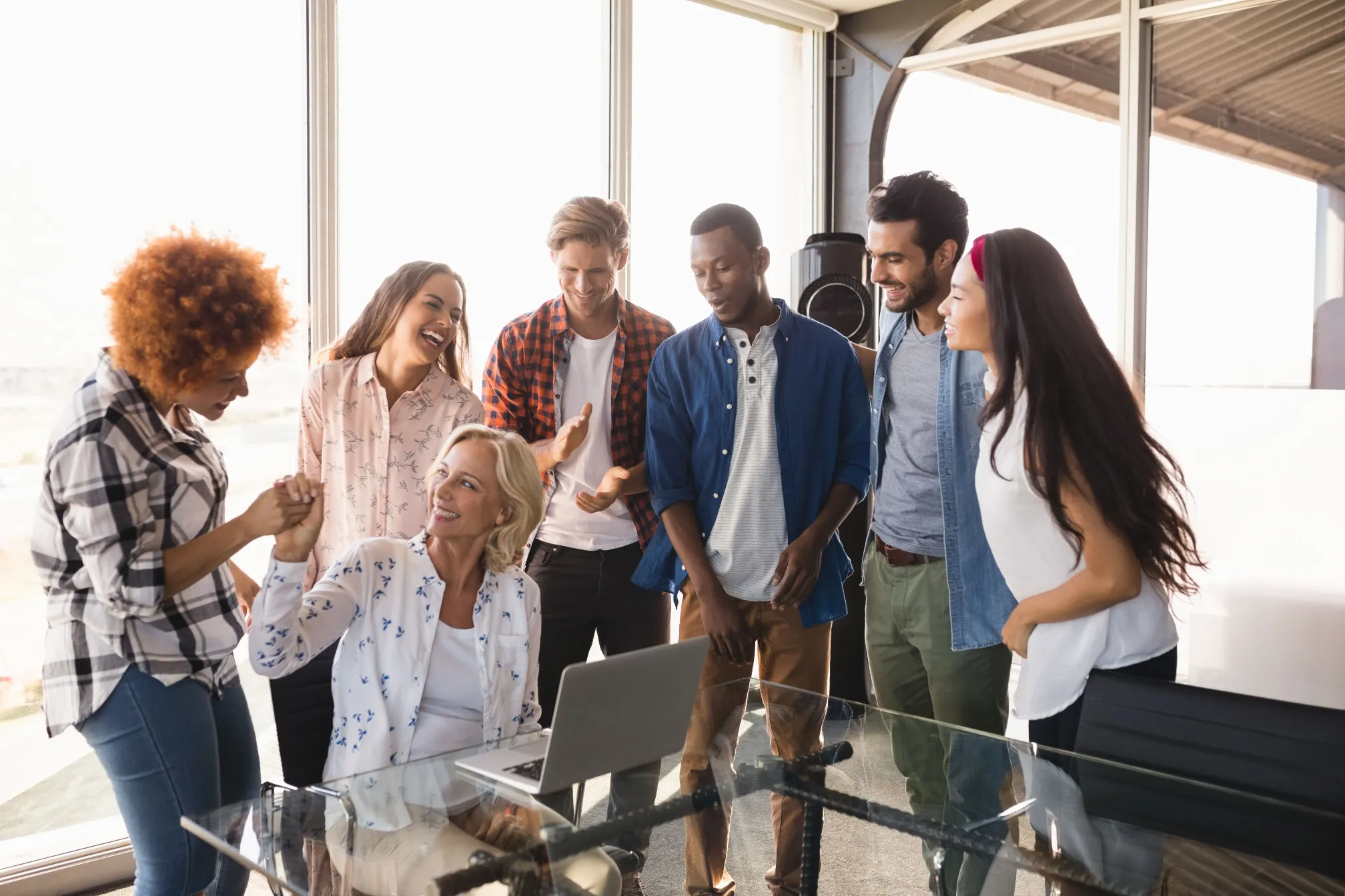Un groupe de jeunes professionnels collaborant autour d'un ordinateur portable dans un bureau moderne, illustrant l'esprit d'équipe et l'innovation sur la plateforme business de Madagasy.com.